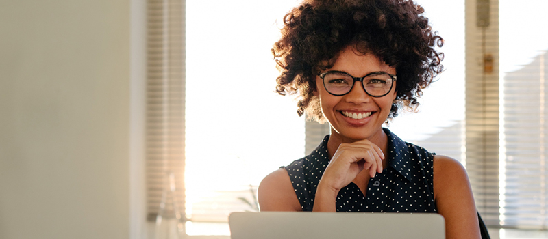 Woman smiling for the camera, working on a computer