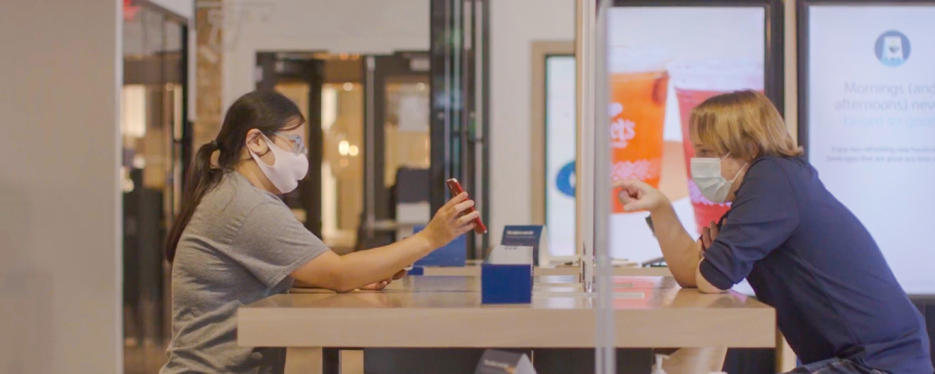 Capital One cafe associate talks to a customer wearing masks